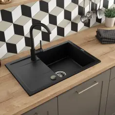 Odkryj najlepsze sposoby na lśniący zlew granitowy bez użycia wybielaczy. Czarny zlew z baterią i akcesoriami kuchennymi na drewnianym blacie.