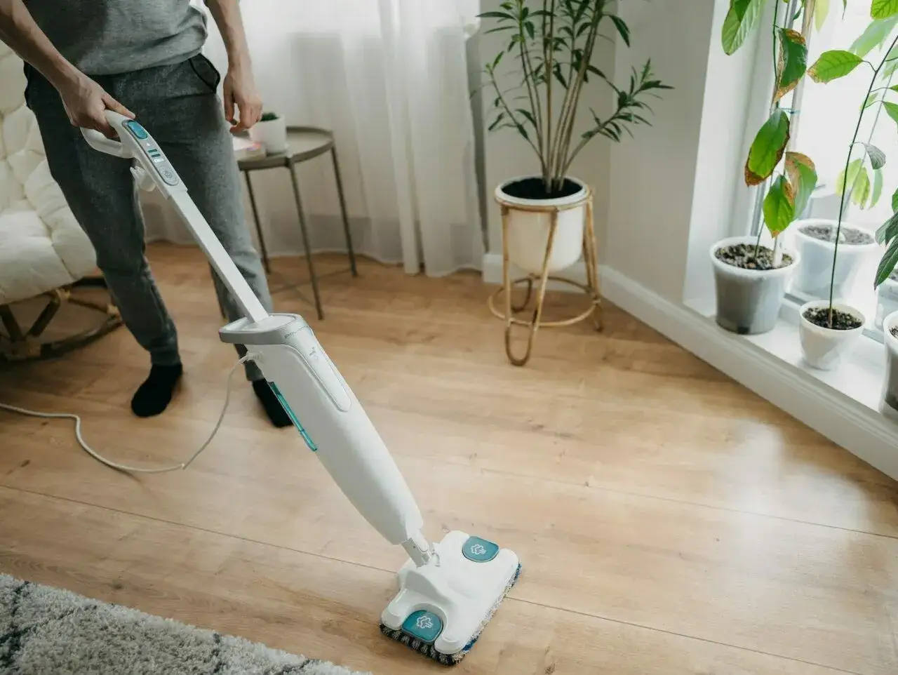 Osoba czyści panele podłogowe mopem parowym. Czy mop parowy nadaje się do paneli? Tak, ten model świetnie sobie radzi!